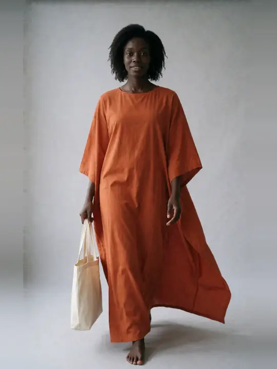 Adaeze in the pose Burnt-orange boubou kaftan, walking with tote